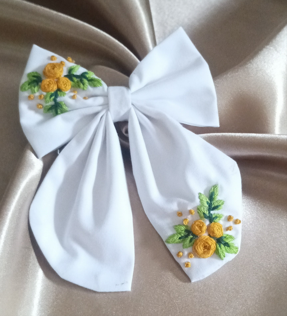Elegant white bow with hand-embroidered yellow floral design