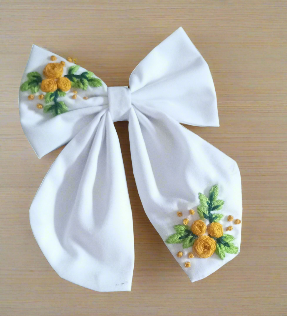 Elegant white bow with hand-embroidered yellow floral design